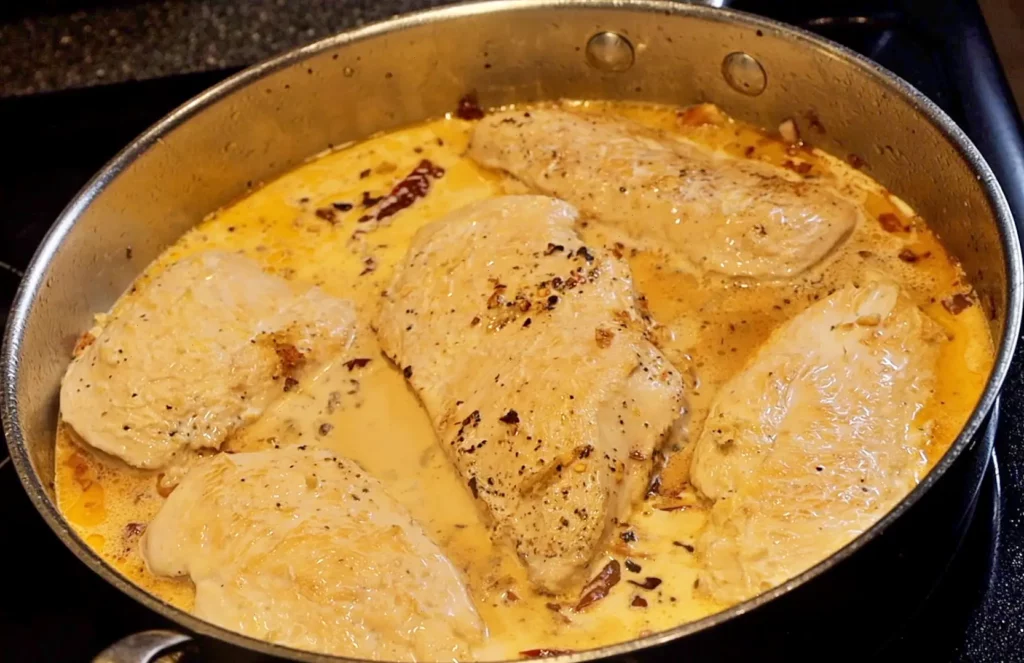 Chicken and cream in pan for Tuscan chicken